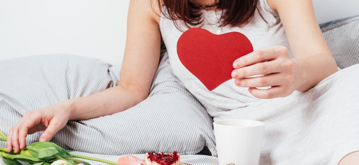 The girl is holding a red heart. Congratulations on Valentine's Day on February 14. Breakfast in bed and a gift