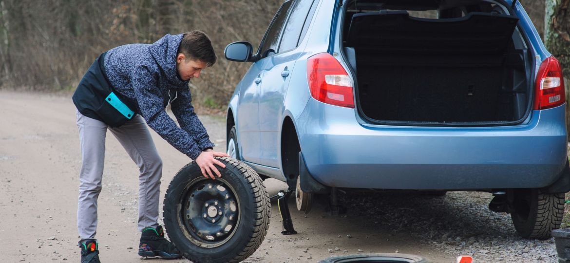 Man is changing tire with wheel on the car