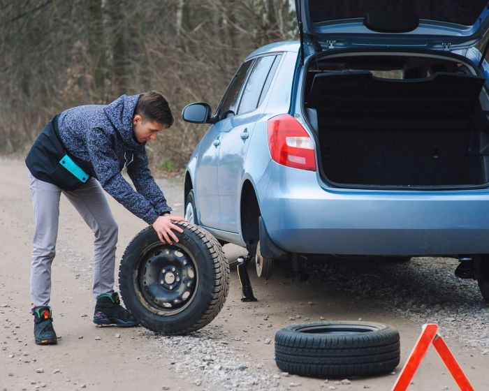 Man is changing tire with wheel on the car