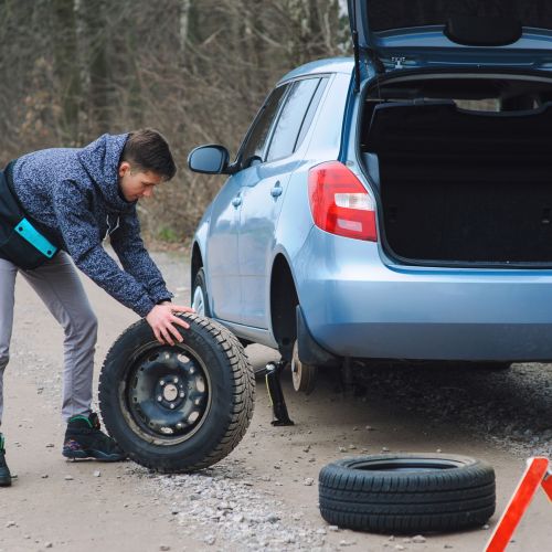 Man is changing tire with wheel on the car