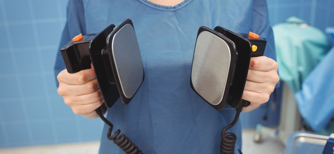 Mid section of female surgeon holding defibrillator at the hospital