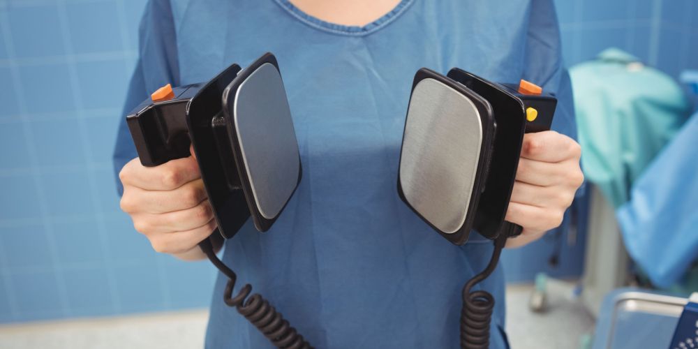 Mid section of female surgeon holding defibrillator at the hospital