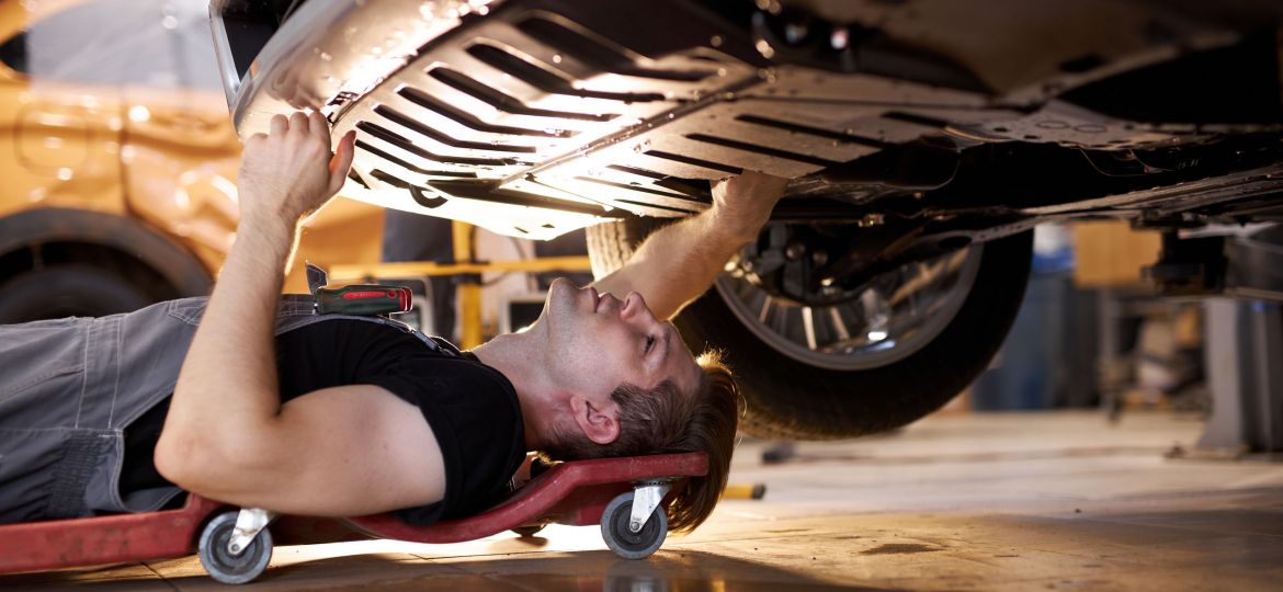 side view on concentrated auto mechanic male working alone on the floor