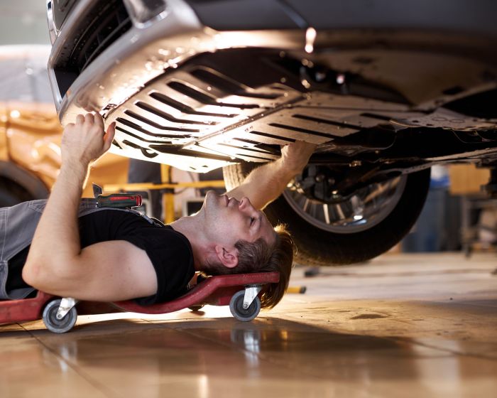 side view on concentrated auto mechanic male working alone on the floor