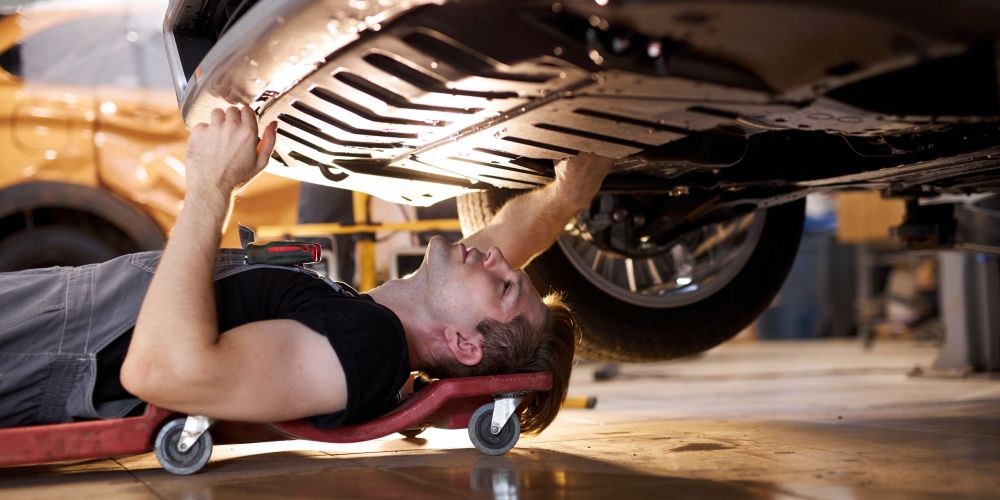 side view on concentrated auto mechanic male working alone on the floor