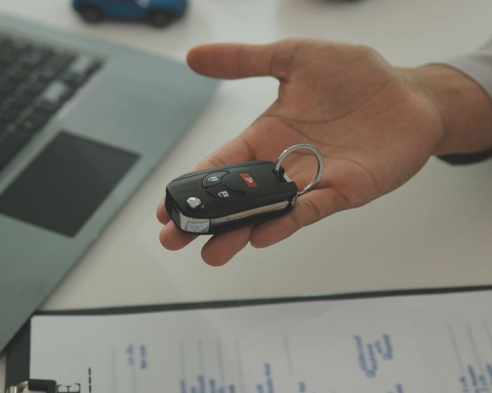 Young man receives a key from car salesman. After agreeing to a